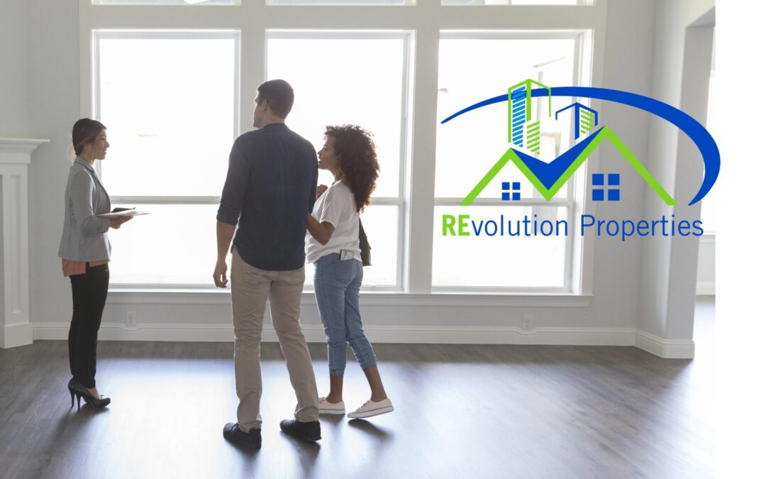 Real estate agent showing a young couple a modern home with large windows, featuring the Revolution Properties logo in blue and green.